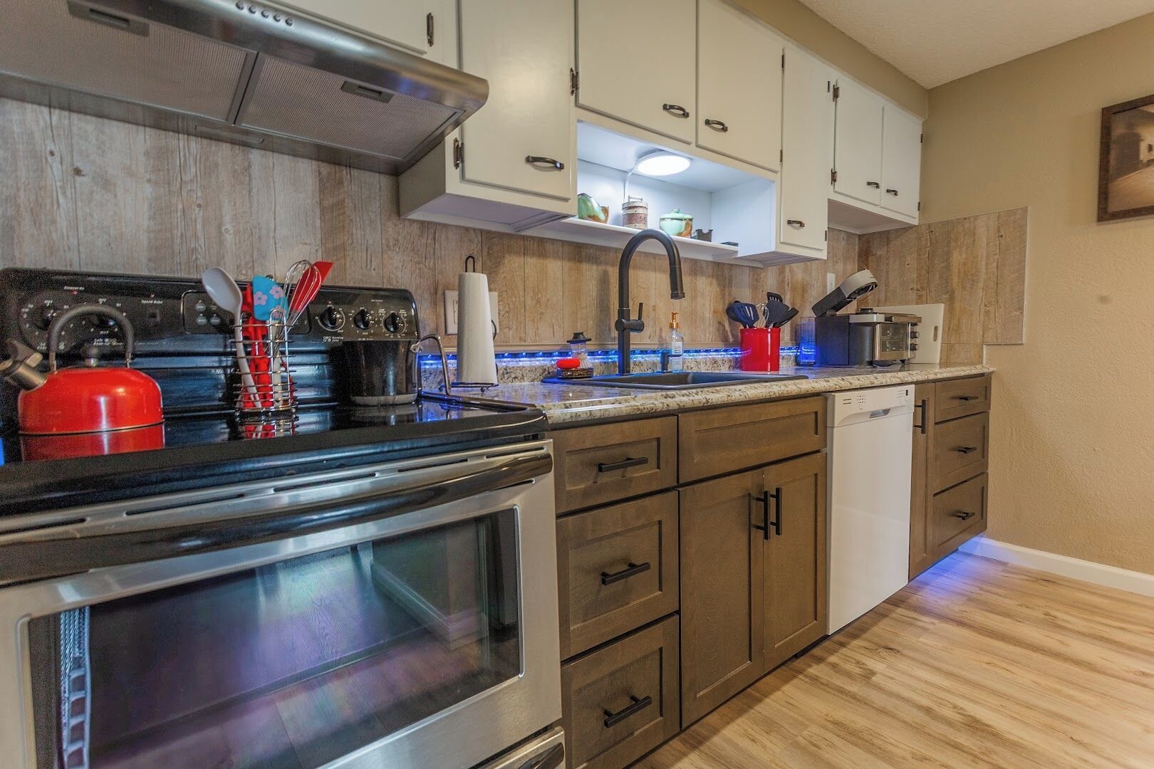 A modern kitchen with stainless steel appliances, wooden cabinets, and a granite countertop.