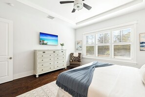 A bedroom with a bed, a dresser, a chair, a painting, and a window with blinds. - New Listing Naturewalk: Private Heated Pool & Spa. EVCharger, Golf Cart & Bikes. (Santa Rosa Beach)