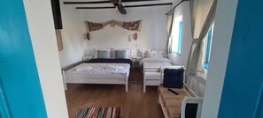 Un dormitorio con dos camas, suelo de madera y una ventana con cortinas.