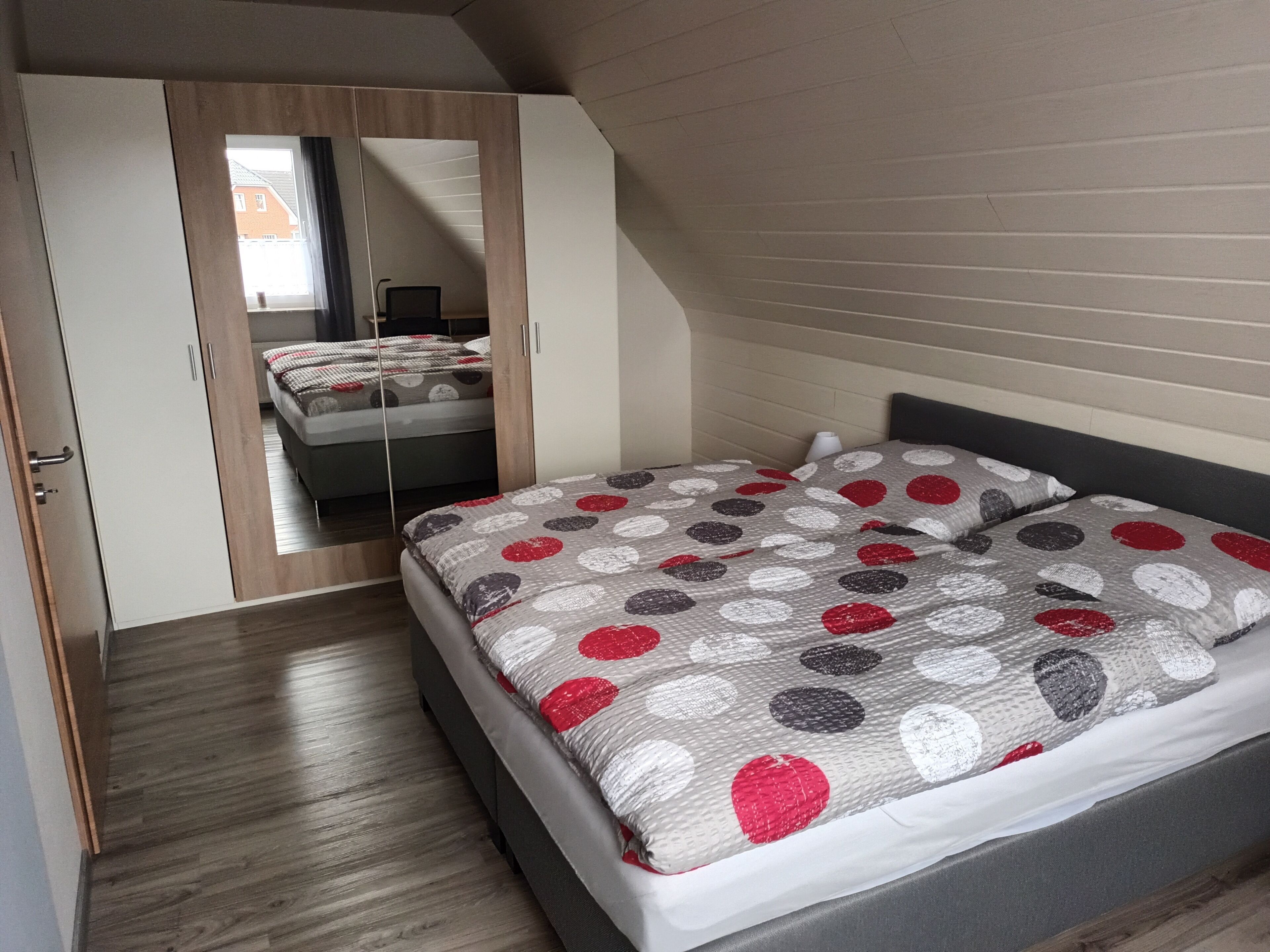 Een slaapkamer met een bed, een kledingkast en een spiegel.