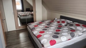 A bedroom with a bed, a wardrobe, and a mirror. - Cozy vacation apartment with balcony. (Aschendorf)