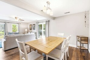 A spacious dining area with a wooden table and white chairs, a sofa with cushions, and a ceiling fan. - Lagoon View Villa in Palmetto Dunes (Hilton Head Island)