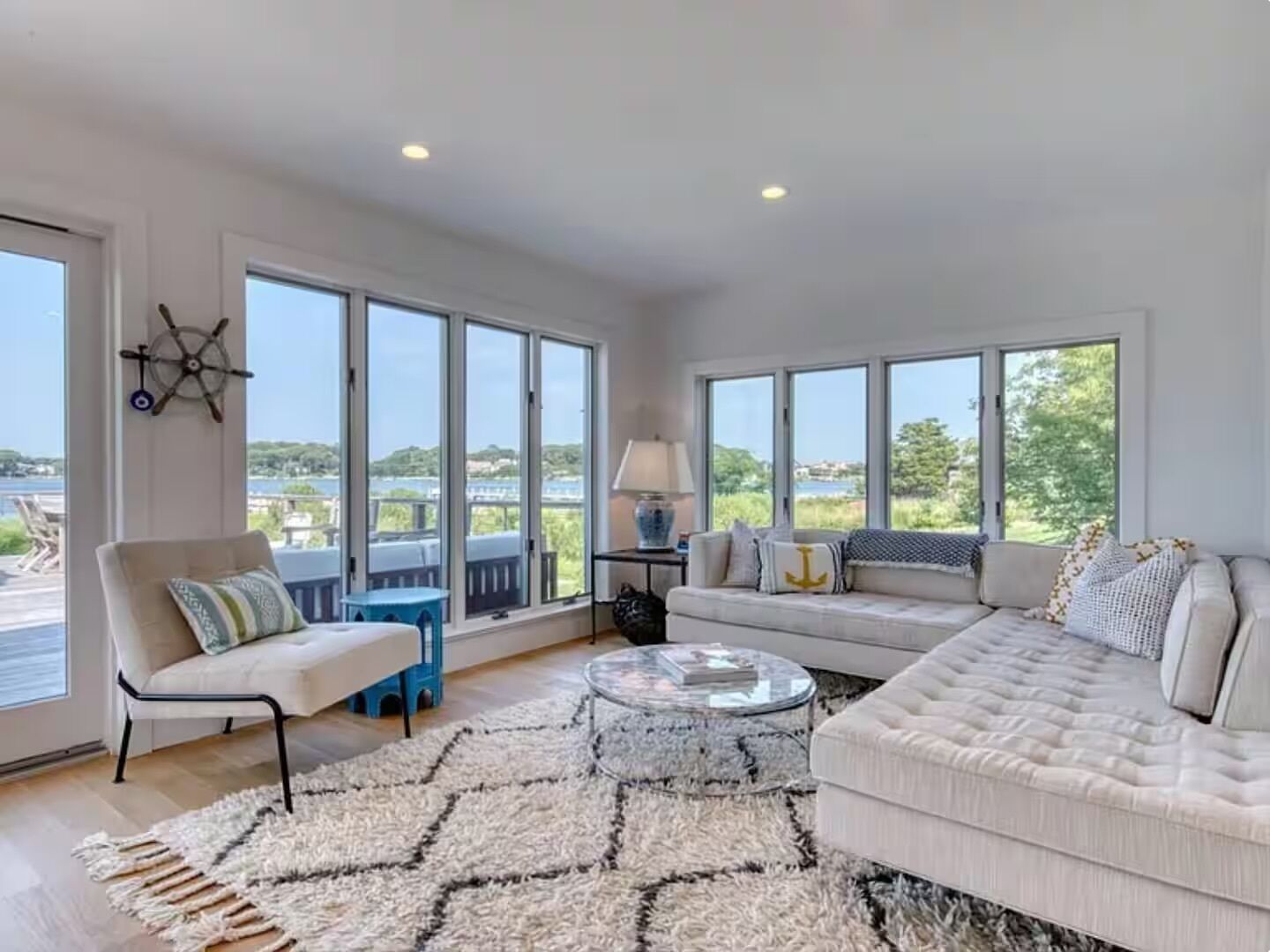 A spacious living room with large windows, a sofa, a chair, a coffee table, and a rug.