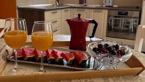 A breakfast tray with watermelon slices, cherries, and orange juice glasses in a modern kitchen with white cabinets and a window. - Beautiful Apartment Bodulo 3 (Povljana)