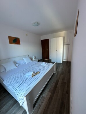 Ein Schlafzimmer mit Bett, Nachttisch, Kleiderschrank und einer Tür.