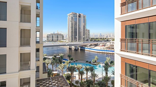 A high-rise building with a view of a river and a bridge. - Silkhaus Stylish 1bdr With Pool Balcony Dubai Creek Harbour (Dubai)