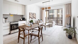 A modern apartment with a kitchen, dining area, and living room. It features a large window, a balcony, and a potted plant. - Silkhaus Stylish 1bdr With Pool Balcony Dubai Creek Harbour (Dubai)