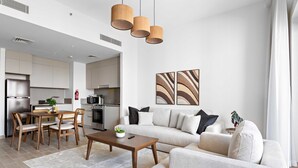 A modern living room with a sofa, coffee table, and dining area. - Silkhaus Stylish 1bdr With Pool Balcony Dubai Creek Harbour (Dubai)