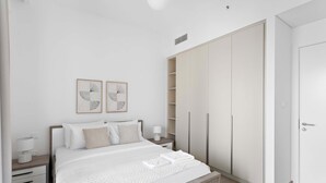 A modern bedroom with a large bed, a nightstand, a wardrobe, and two framed artworks on the wall. - Silkhaus Stylish 1bdr With Pool Balcony Dubai Creek Harbour (Dubai)