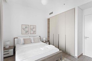 A modern bedroom with a large bed, a nightstand, a wardrobe, and two framed artworks on the wall. - Silkhaus Stylish 1bdr With Pool Balcony Dubai Creek Harbour (Dubai)