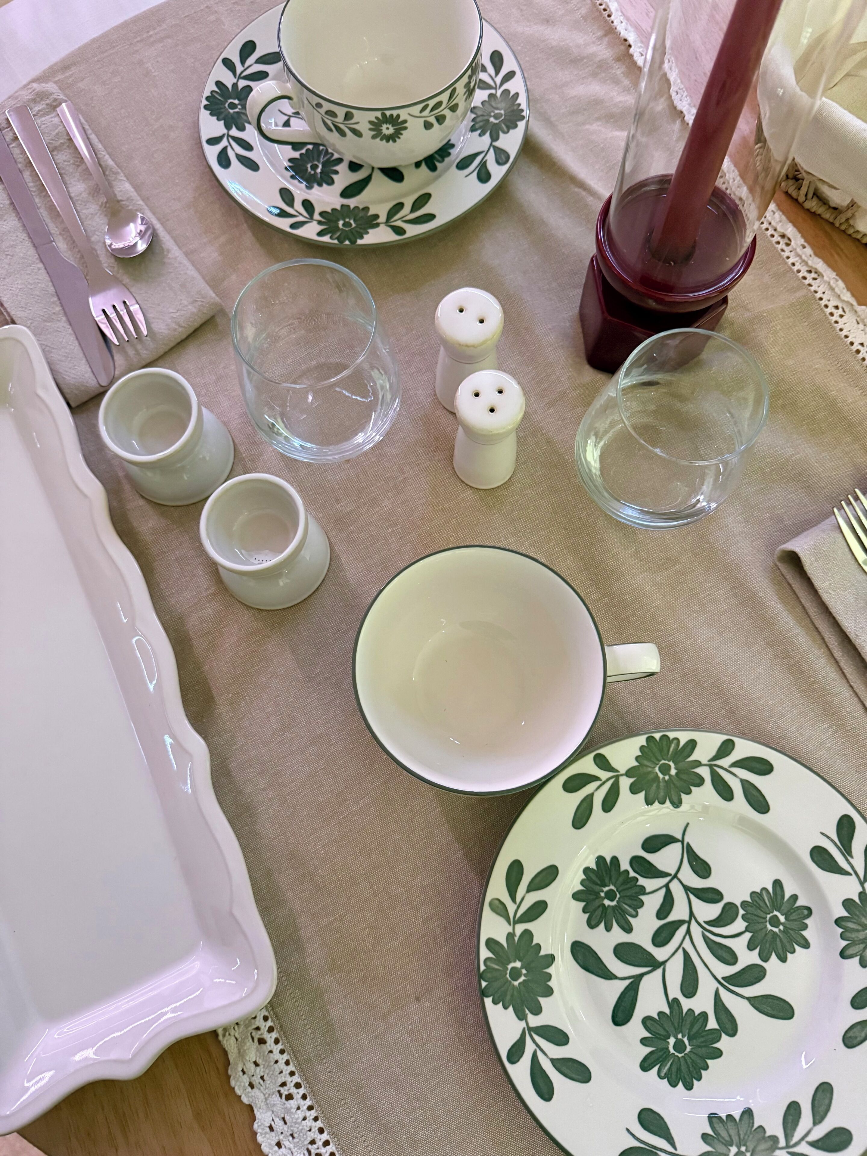 A table set with plates, bowls, cups, and cutlery, arranged on a tablecloth.