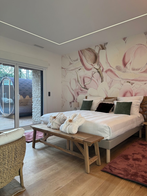 A modern bedroom with a large bed, a bench, and a view of the outdoors. - 1h30 from Paris - Romantic spa suite and private sauna on a country terrace (Vimory)