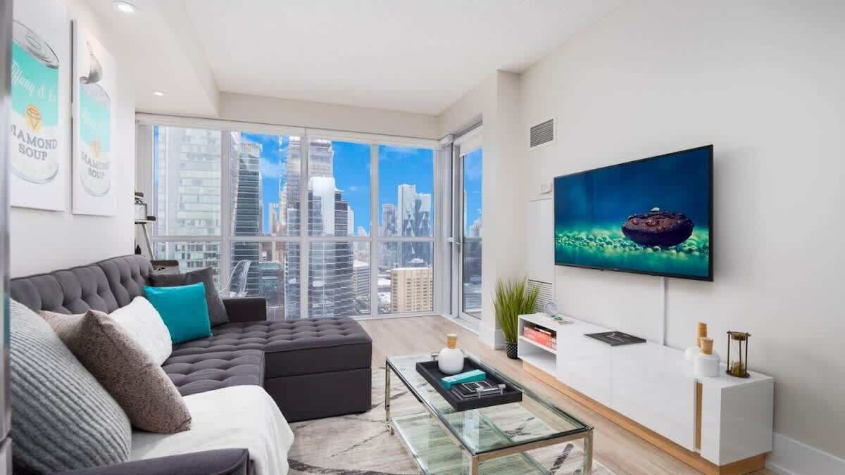 The spacious living room with floor-to-ceiling windows offers breathtaking city views
