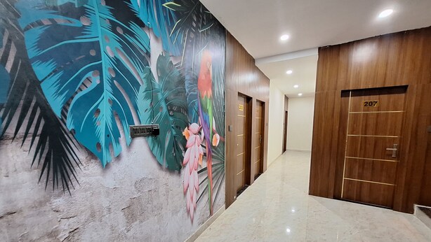 A hallway with a mural, wooden doors, and a marble floor. - Hotel Gravity by De Tulip (Bhopal)