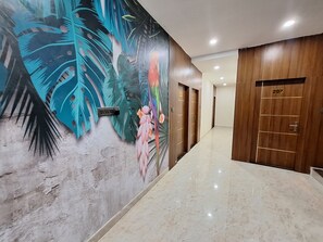 Un corridoio con un murale, porte in legno e pavimento in marmo.