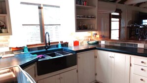 Een keuken met witte kastjes, een zwart aanrecht en een roestvrijstalen spoelbak.