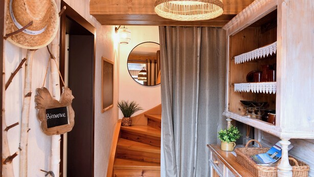 A wooden interior with a staircase, a welcome sign, a mirror, and a shelf with items. - Gîte Vigne en fleur (Ribeauvillé)