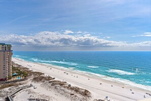 A beach with a hotel in the background, a clear sky, and the ocean. - Stunning Gulf Views, Multiple pools, Perfect blend of relaxation and convenience (Destin)