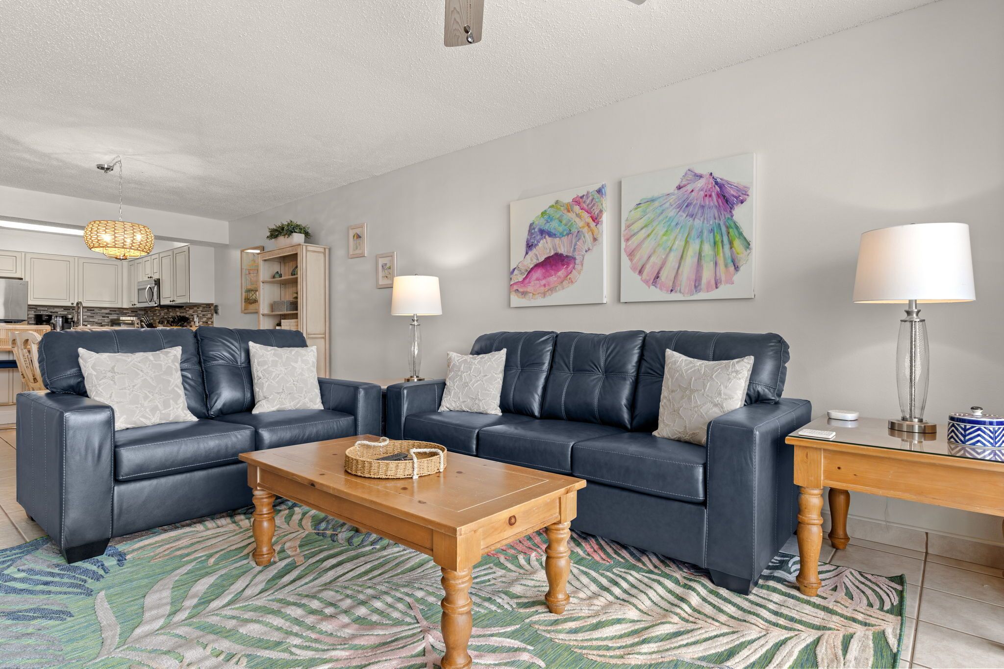 Ein modernes Wohnzimmer mit einem blauen Ledersofa, einem Holztisch und einem gemusterten Teppich.