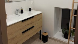 Une salle de bain moderne avec un meuble-lavabo blanc, un grand miroir et un plancher en bois.