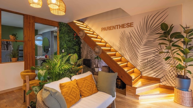 Ein modernes Wohnzimmer mit Treppe, einem weißen Sofa und diversen Pflanzen.
