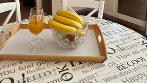 A kitchen with white cabinets, a microwave, and a window. There is a tray with a glass of orange juice and a bowl of bananas and apples on the table. - Beautiful Apartment Bodulo 4 (Povljana)
