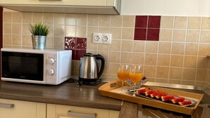 A kitchen with a microwave, kettle, and a tray with sliced fruit and glasses of orange juice. - Beautiful Apartment Bodulo 4 (Povljana)