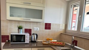 A compact kitchen with white cabinets, a microwave, a kettle, and a sink. - Beautiful Apartment Bodulo 4 (Povljana)