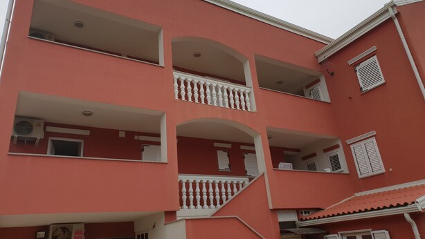 A multi-story building with balconies, air conditioning units, and a tiled roof. - Beautiful Apartment Bodulo 4 (Povljana)