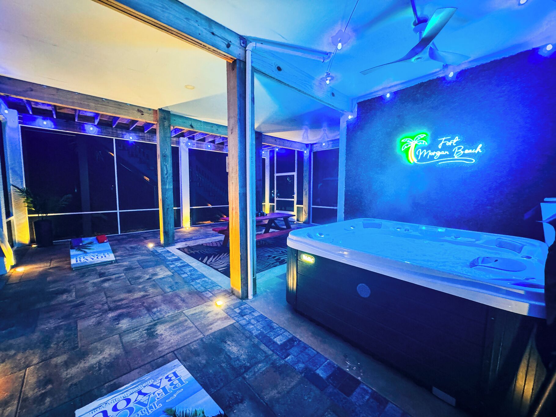 An outdoor hot tub area with a neon sign reading "Funt Morgan Beach".