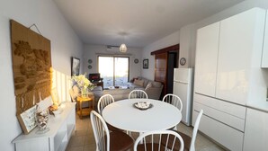 Una cocina moderna con armarios blancos, una mesa de comedor con sillas y un gran tapiz decorativo en la pared.