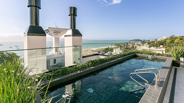 A rooftop infinity pool with a clear view of the ocean and a distant shoreline. - Gastronomy | Swimming pool | Beachfront #CAJU04 (Florianópolis)