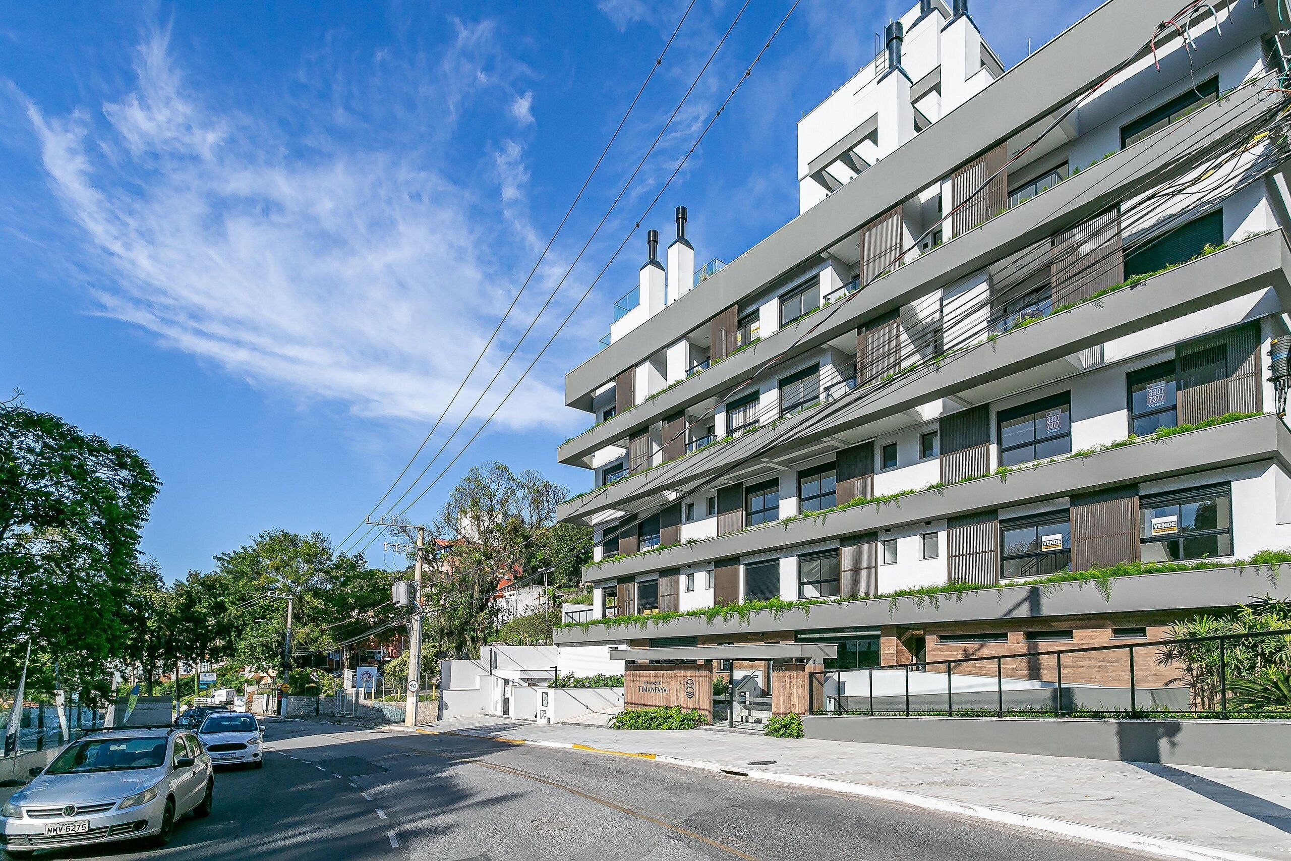 A multi-story hotel with balconies, a covered entrance, and a clear sky.