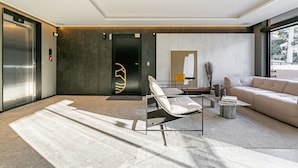 A modern living room with a sofa, a lounge chair, a coffee table, and a large window. - Gastronomy | Swimming pool | Beachfront #CAJU04 (Florianópolis)