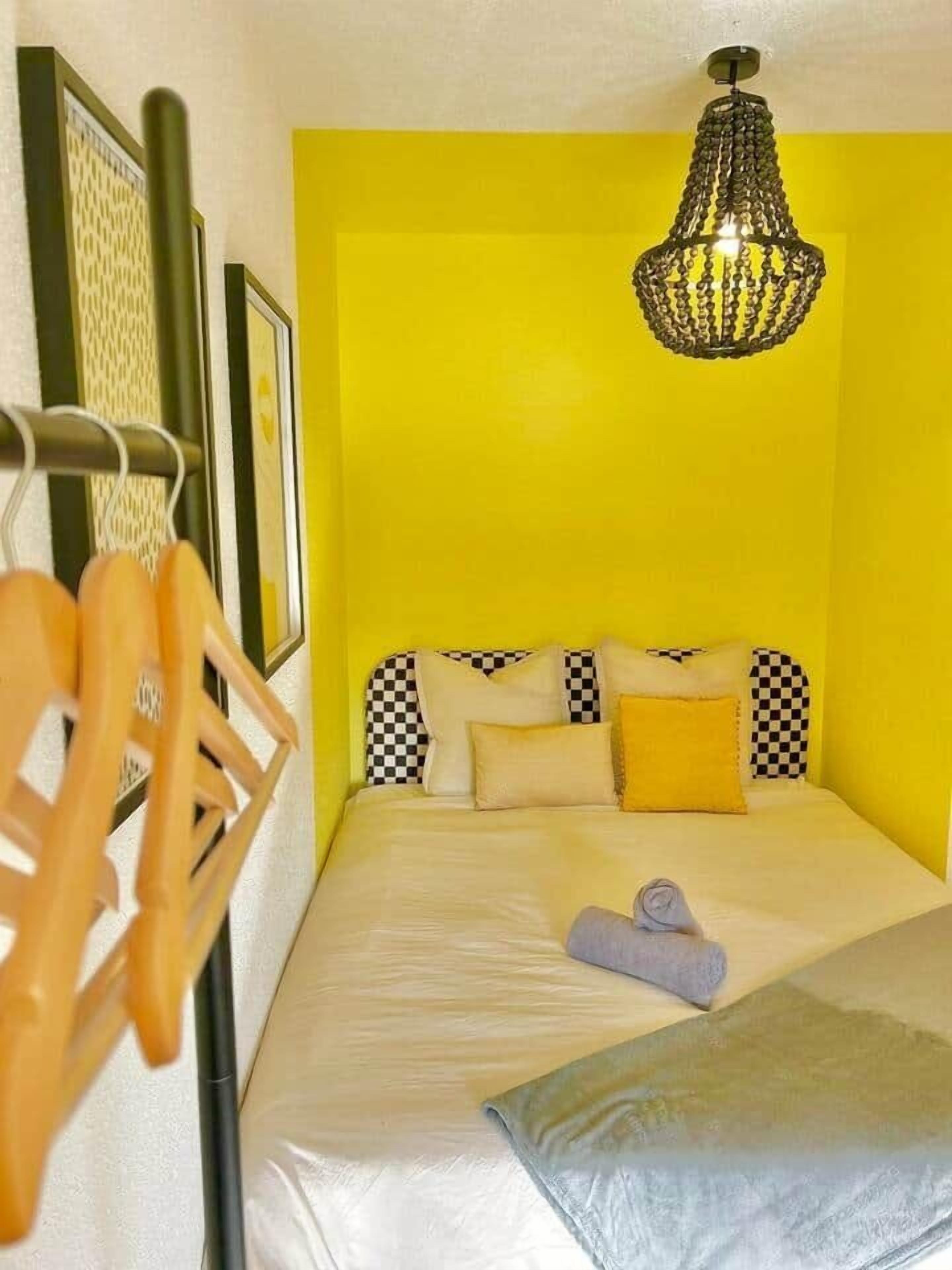 A room with a bed, a hanging light fixture, and a wall-mounted rack.