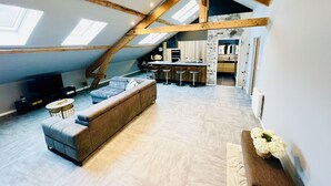 A loft-style living space with a large sofa, a dining area with bar stools, a kitchen, and skylights. - Spacious, modern, quiet - Hypercentre Gérardmer (Gérardmer)