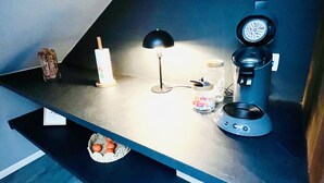 A kitchen counter with a clock, a coffee maker, a lamp, and a basket of oranges. - Spacious, modern, quiet - Hypercentre Gérardmer (Gérardmer)