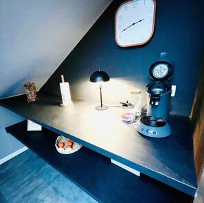 A kitchen counter with a clock, a coffee maker, a lamp, and a basket of oranges. - Spacious, modern, quiet - Hypercentre Gérardmer (Gérardmer)