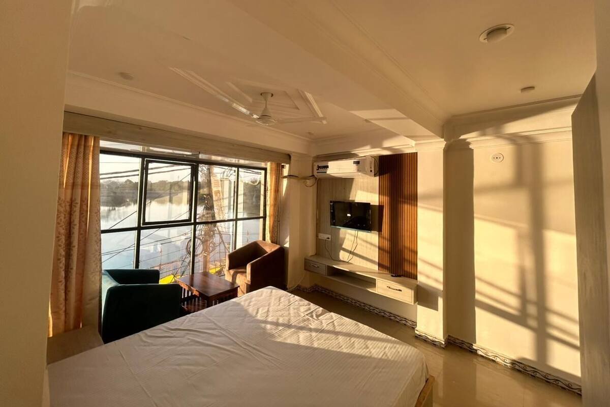 Een hotelkamer met een bed, een bureau, een stoel, een televisie en een raam met gordijnen.