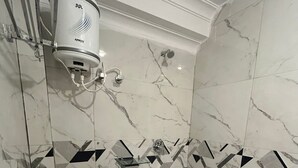A bathroom with a toilet, a shower, and a hand dryer mounted on the wall. - Soni's Mansion Shivsagar (Khajuraho)