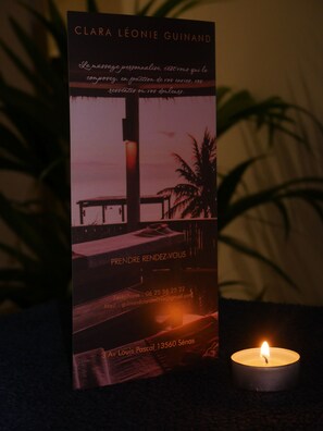 A book titled 'CLARA LÉONIE GUINAND' with contact information and a candle. - Le Petit Provençal (Sénas)