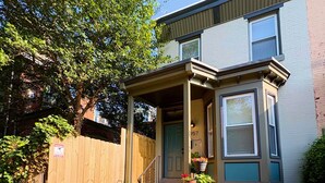 A two-story residential building with a front porch, a wooden fence, and a brick pathway leading to the entrance. - Amazing 2BdRoom Townhome & Free Street Prkng in the University Section of Philly (Philadelphia)