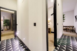 Ein modernes Interieur mit einem geometrisch gemusterten Boden, einem Essbereich mit Holzmöbeln und einer Topfpflanze.