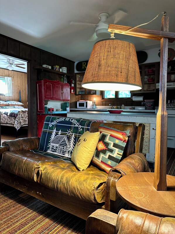 A cozy living room with a leather sofa, a wooden coffee table, and a hanging lamp.