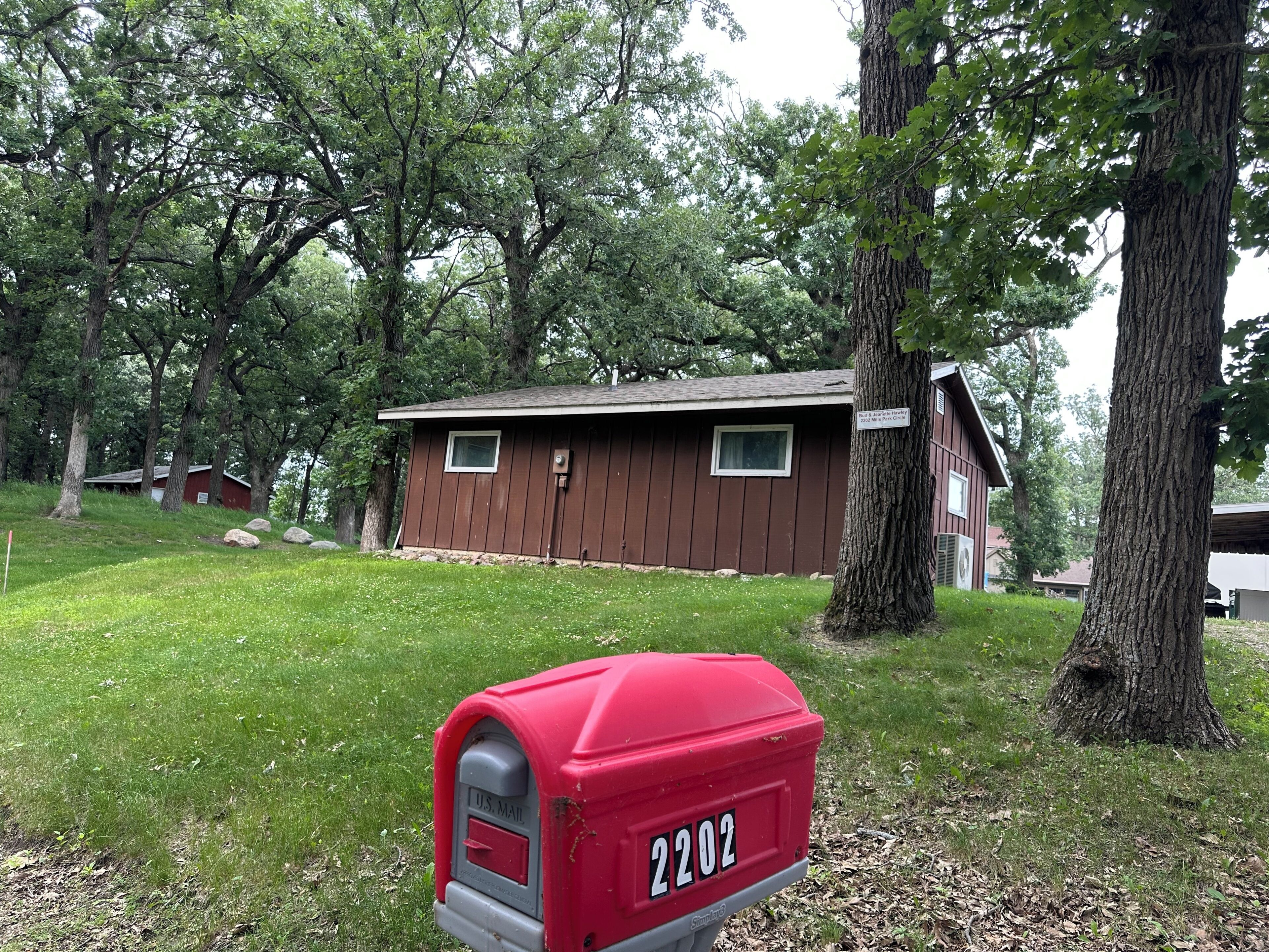A small brown building with a red mailbox labeled '2202' in front.