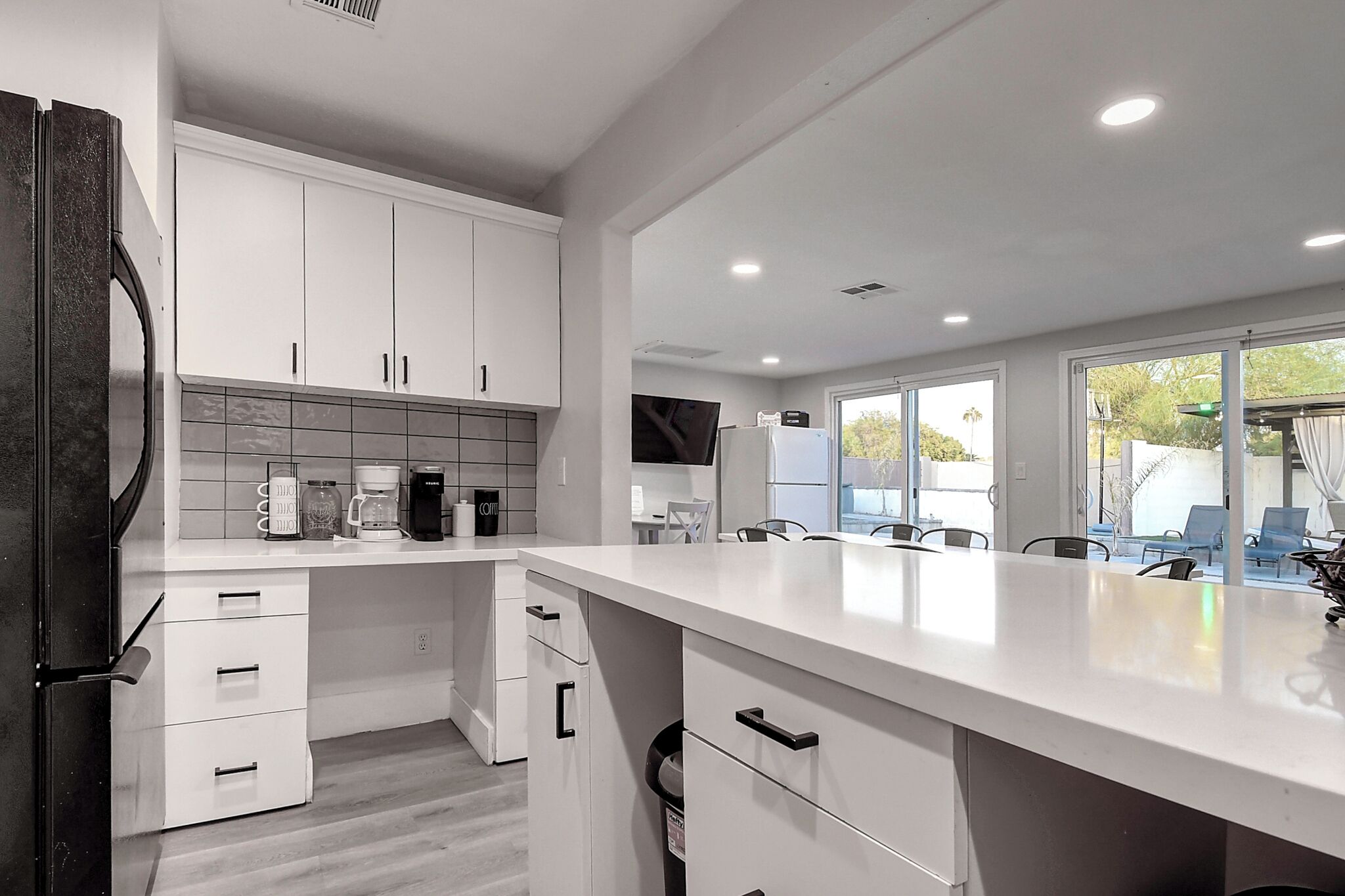 Una cocina moderna con armarios blancos, una isla grande y vistas al exterior.