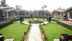 A courtyard with a central pathway, surrounded by uniform buildings with balconies and a circular garden area. - THE SPARROW NEST ECO COTTAGE (Gop)