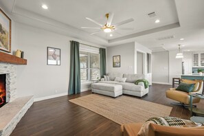 A modern living room with a fireplace, a ceiling fan, and a dining area. - Lakefront Getaway w/ Hot Tub, Kayaks & Spacious Deck (Crosby)