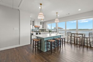 A modern kitchen with a large island, bar stools, and a view of the water. - Lakefront Getaway w/ Hot Tub, Kayaks & Spacious Deck (Crosby)