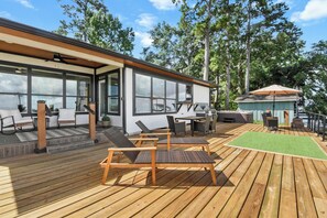 A modern outdoor deck with wooden furniture, a green artificial turf area, and a covered seating area. - Lakefront Getaway w/ Hot Tub, Kayaks & Spacious Deck (Crosby)